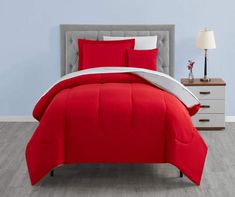 a bed with red comforter and pillows in a room