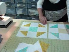 a woman is working on some quilts at a sewing machine and cutting them into squares