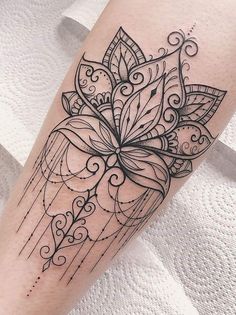 a black and white photo of a tattoo on the leg with an intricate flower design