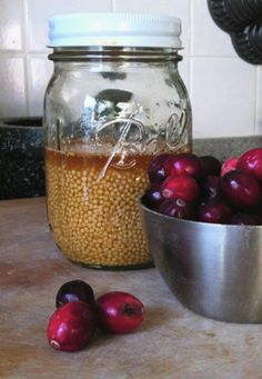 a bowl of beans next to a glass jar filled with some kind of liquid on top of a counter