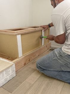 a man kneeling down on the floor working on some wood pieces that are being built