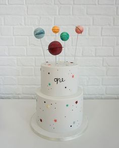 there is a white cake with three planets on it and the words one written in black