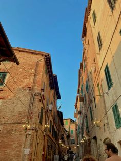 people are walking down an alleyway in the old part of town on a sunny day