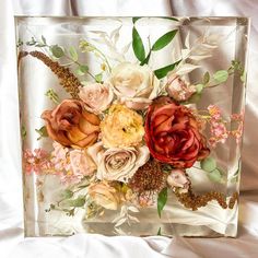 there is a glass box with flowers in it