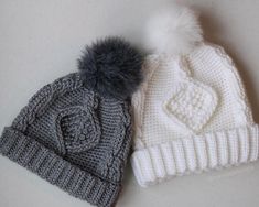 two knitted hats with pom - poms on the top one is grey and white