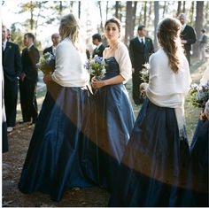 two women in blue dresses standing next to each other with people looking on behind them