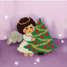 a cross stitch christmas ornament with an angel next to a tree