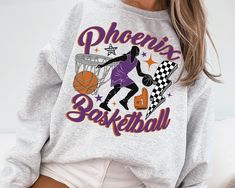 "WELCOME TO MY STORE ♥️ -This Retro Phoenix Mercur Crewneck Sweatshirt \\ T-Shirt, Phoenix Mercur Fan Shirt, Mercury T-Shirt, Vintage Phoenix Mercur Women's Basketball. -Please check Color and Size Charts before placing the order. You can find them in the listing's photos (Depending on what device you are viewing this listing colors may vary slightly). -Returns and exchanges are accepted only if there are defects \"No Extra Costs\" _UNISEX T-SHIRT * 100% cotton for solid colors * Heather colors are 35% ring-spun cotton, 65% polyester * Sport Grey is 90% cotton, 10% polyester #Care: Machine wash: warm (max 40C or 105F), Tumble dry: low, Iron & steam or dry: low  _UNISEX CREWNECK SWEATSHIRT * 50% cotton, 50% polyester * Air jet yarn for a softer feel & no pilling * 1x1 athletic rib cuffs & w Basket Vintage, Women's Basketball, Fan Shirts, Womens Basketball, Size Charts, Shirt Price, Crewneck Sweatshirt, Solid Colors, Sweat Shirt