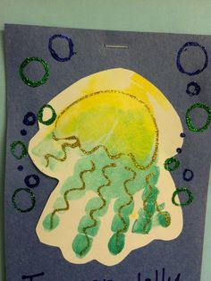 a child's handprinted jellyfish on a blue background with green bubbles