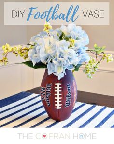 a football vase filled with blue flowers on top of a striped tablecloth covered table