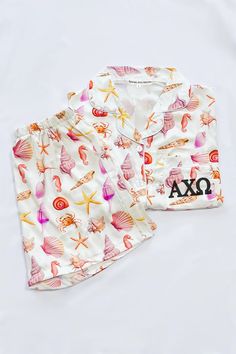 two pieces of pajamas with seashells and starfish on them, one is white