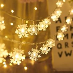 snowflake lights are hanging from a string in front of a poster that reads,