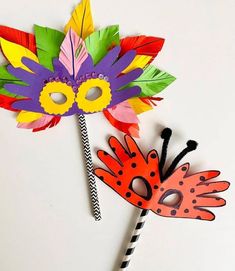 a colorful mask and flower on top of a black and white striped paper straw stick