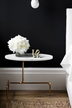 a white flower sitting on top of a table next to a vase filled with flowers