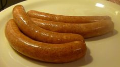 three sausages on a white plate sitting on a table