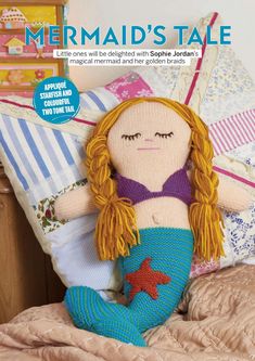 a knitted mermaid doll sitting on top of a bed