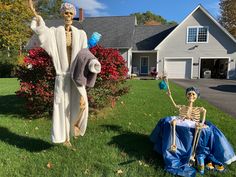 two skeletons sitting in the grass next to a lawn with a skeleton statue on it