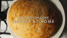 a round loaf of bread sitting on top of a white plate with the words, sourdough loaf hearty at home