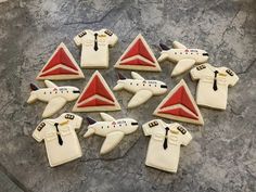 nine decorated cookies in the shape of planes and t - shirts are arranged on a table