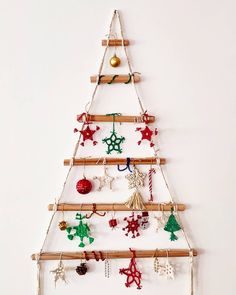 a christmas tree made out of wooden sticks and ornaments hanging on the wall with white background