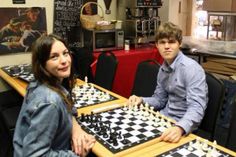 two people sitting at a table playing chess