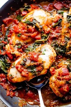 a skillet filled with chicken and spinach covered in sauce