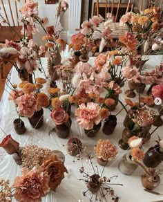 a table topped with lots of vases filled with different types of flowers and plants