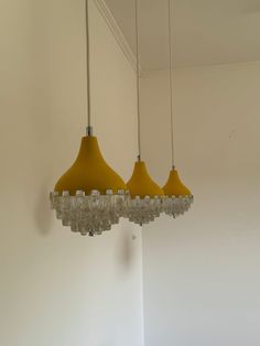 three yellow lights hanging from the ceiling in a room with white walls and flooring