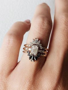 a woman's hand with two rings on it and an engagement ring in the middle