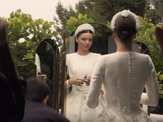 two women in white dresses are looking at their cell phones