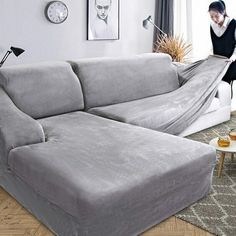 a living room filled with furniture and a large gray couch covered in a blanket on top of a hard wood floor