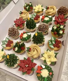 cupcakes decorated with flowers and greenery are displayed in a box on a table