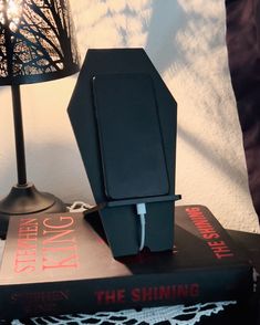 two books are stacked on top of each other with a lamp in the corner next to them