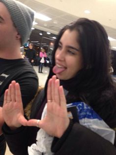 a man and woman standing in an airport with their hands up to the camera smiling