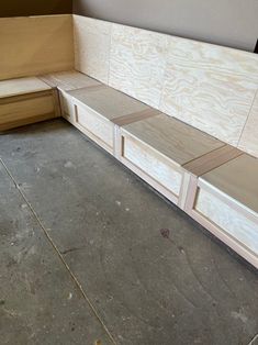 a wooden bench sitting on top of a cement floor next to a box filled with plywood