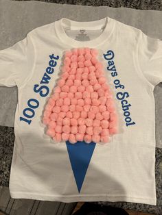 a white t - shirt with pink cotton balls in the shape of a christmas tree