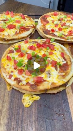 three pizzas with different toppings sitting on top of a wooden table