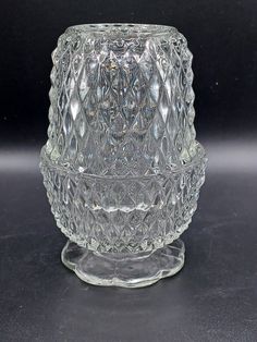 a clear glass candle holder sitting on top of a black countertop next to a gray wall