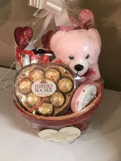 a teddy bear sitting in a basket filled with chocolates