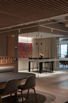 a dining room table and chairs in front of a glass wall with an abstract painting on it