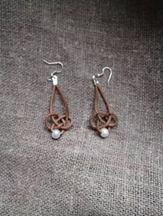 the earrings are made out of leather and have white pearls on them, as well as silver