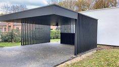 a black metal structure sitting in the middle of a yard next to a white building