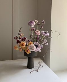 a vase filled with flowers sitting on top of a white table next to a wall