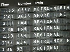 an airport sign showing the time and train times