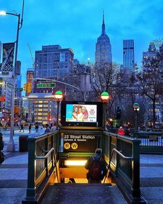 a person is sitting on the stairs in front of a bus at night with city lights behind them