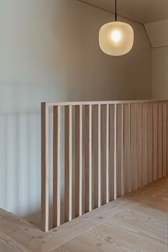 an empty room with wooden slats and a light fixture hanging from the ceiling above it