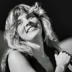 a black and white photo of a woman with her hair blowing in the wind smiling