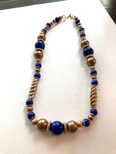 "Vintage Signed V.A. Navy and Bronze Beaded Necklace. The beads of this necklace are plastic. There are some gold tone spacers and bead caps. There are bronze small beads and larger beads and twisted beads. The navy blue beads are also a variety of sizes. The clasp is a simple hook signed V.A. It is 18\" long. It looks like a heavier necklace then what it is. It is in excellent condition. No missing beads, no chips, no scratches or color discolor." Elegant Gold Beaded Necklaces With Metal Beads, Elegant Gold Metal Beaded Necklaces, Gold Polished Beads For Costume Jewelry, Metal Necklace With Spacer And Round Beads, Gold Necklaces With Polished Metal Beads, Metal Beaded Necklaces For Jewelry Making, Gold Metal Beaded Necklaces With Faceted Beads, Gold Costume Jewelry Beaded Necklace With Polished Beads, Gold Beaded Costume Jewelry Necklaces