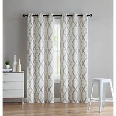 the curtains in this room are white and beige with an intricate pattern on them,