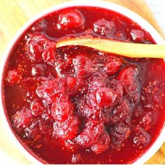 a wooden spoon in a bowl filled with cranberry sauce on top of a table